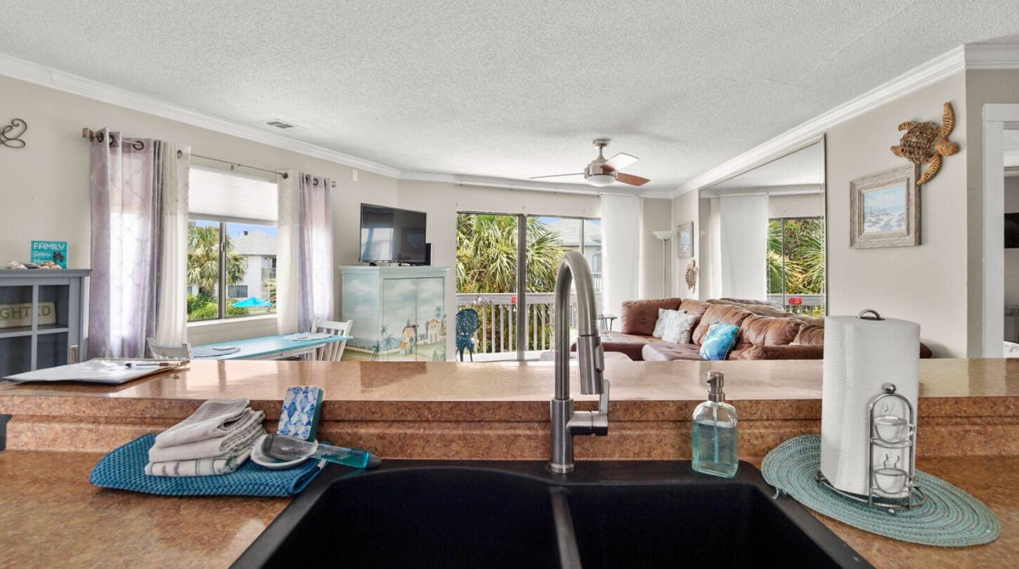 Una cocina moderna con un lavamanos, una zona de comedor con una mesa, un sofá y un balcón con vistas.