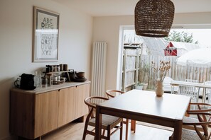 A wooden dining table with chairs, a hanging light fixture, and a wall-mounted alphabet chart. - bumpkin. Stylish Coastal Home. Walk to Beach & Award-Winning Seafood. Sleeps 6 (West Mersea)