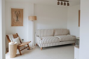 A living room with a striped sofa, a wooden chair, a lamp, and a framed picture on the wall. - bumpkin. Stylish Coastal Home. Walk to Beach & Award-Winning Seafood. Sleeps 6 (West Mersea)