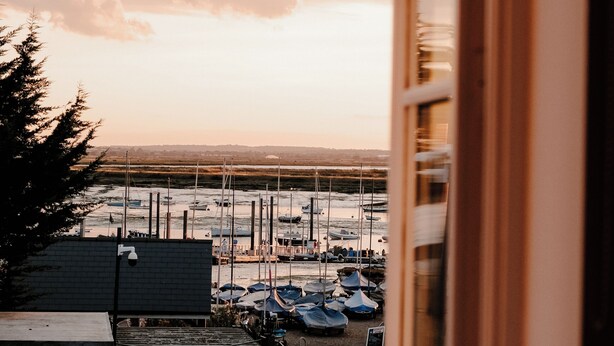 Vista di un porto turistico con imbarcazioni ormeggiate, cielo sereno e un edificio sullo sfondo.