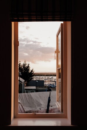A window with a view of a marina, a covered area, and a tree. - bumpkin. Stylish Coastal Home. Walk to Beach & Award-Winning Seafood. Sleeps 6 (West Mersea)