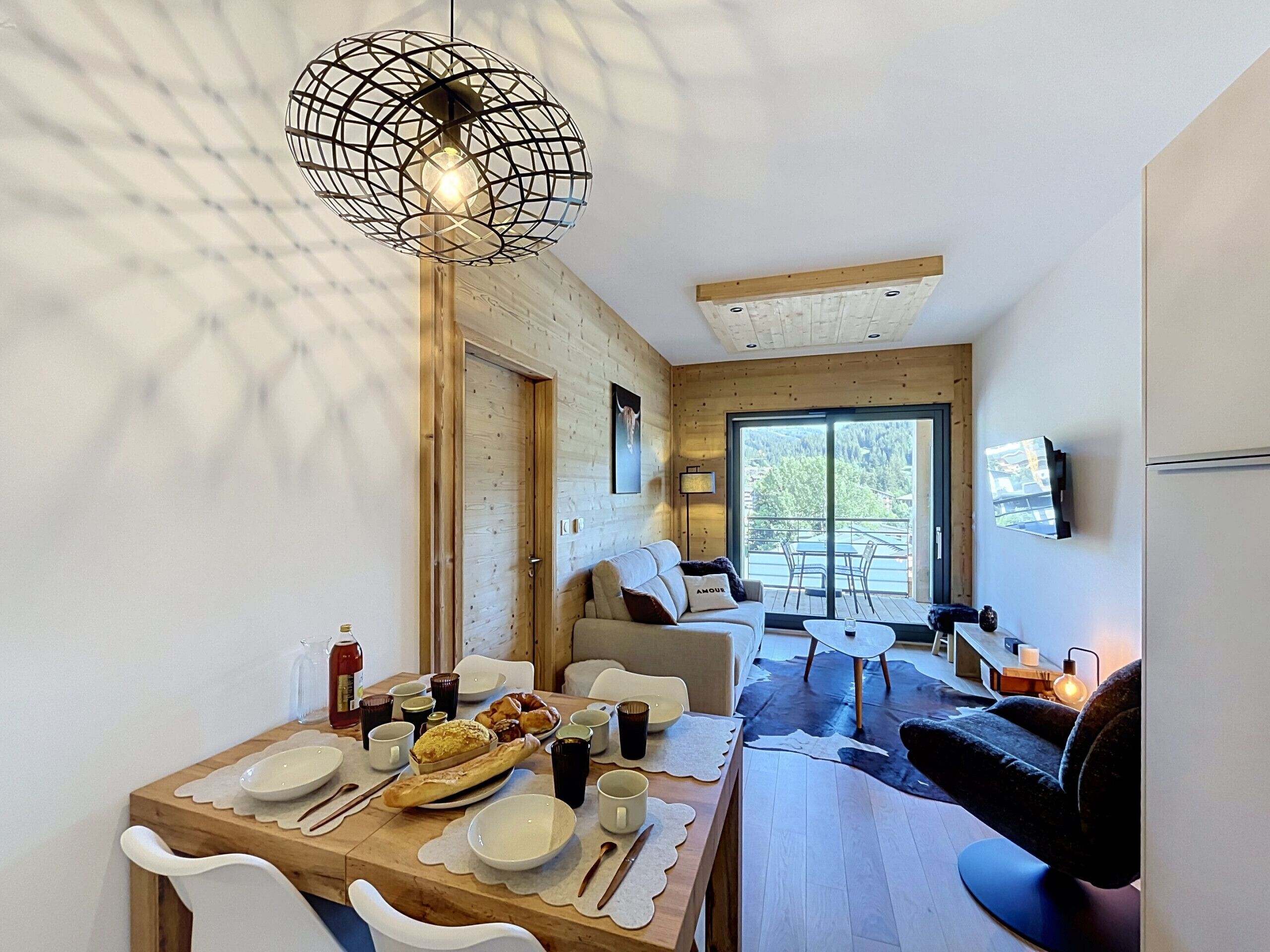 A modern interior with a dining area, wooden walls, a large window, and a ceiling light fixture.