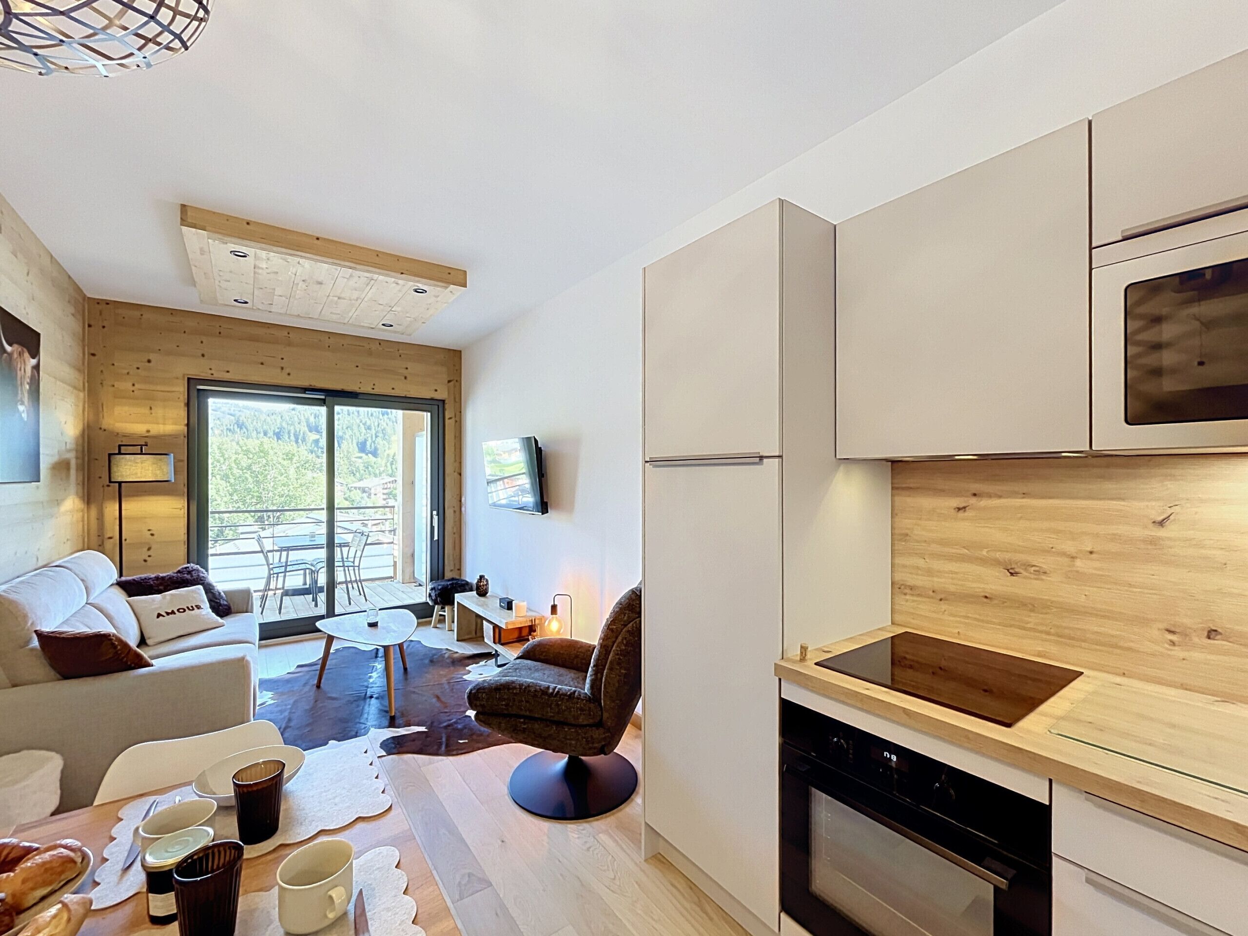 Una cocina moderna con horno integrado, un comedor con mesa y sillas, y un sofá.