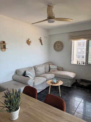 A modern living room with a sofa, a dining table, and a ceiling fan.