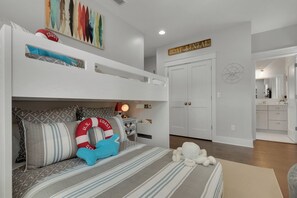 A bedroom with a bunk bed, a bed with striped bedding, a nightstand with a lamp, and a wall with a compass decoration. - Set Sail for Goin’ Coastal pet friendly 3 bedroom luxury home (Watersound)