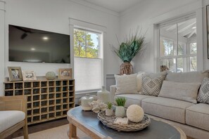 A living room with a television, a sofa, a coffee table, and a decorative basket. - Set Sail for Goin’ Coastal pet friendly 3 bedroom luxury home (Watersound)