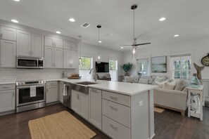A modern kitchen with white cabinetry, stainless steel appliances, and pendant lighting. - Set Sail for Goin’ Coastal pet friendly 3 bedroom luxury home (Watersound)