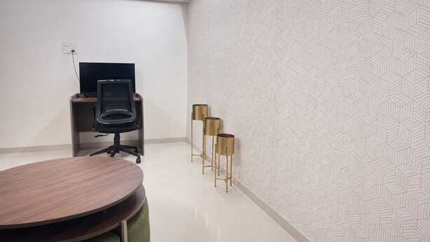 A conference room with a round table, a black office chair, a television on a stand, and three gold-colored floor lamps. - lavender residense MIDC andheri east (Mumbai)