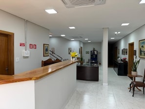 A reception area with a wooden counter, a fire alarm panel, and a central alarm station sign. - WN HOTEL (Barretos)