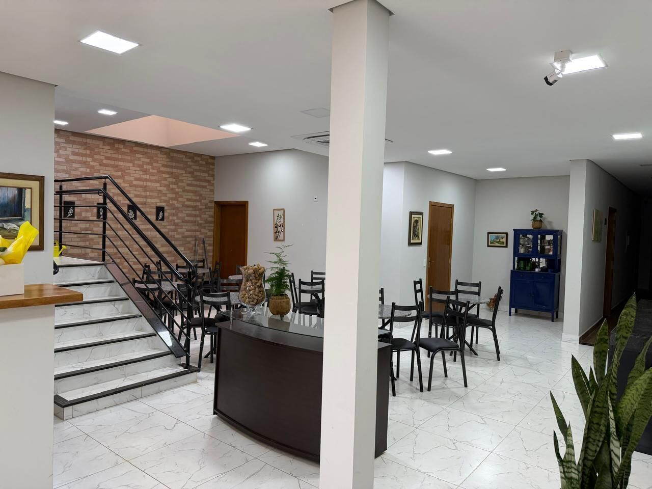 A hotel lobby with a staircase, a reception desk, and a dining area.