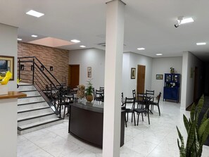 A hotel lobby with a staircase, a reception desk, and a dining area. - WN HOTEL (Barretos)
