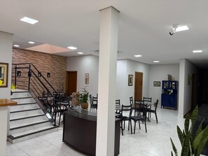 Un vestíbul d'hotel amb una escala, una recepció i una zona de dinar.