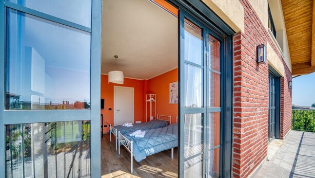 A modern bedroom with a bed, a hanging light fixture, and a view through large glass doors. - Single Use   Arielle Dombasle (Roata Paoletti)