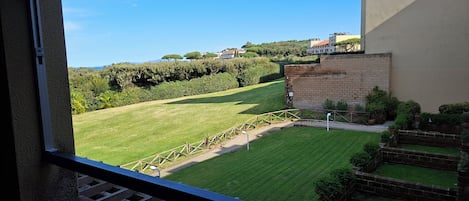 A view from a balcony overlooking a well-maintained lawn with a brick wall and a wooden fence.