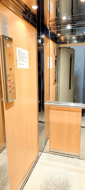 An elevator interior with a wooden panel and a control panel with buttons. - Premium apartment in Acropolis (Athens)