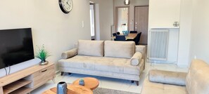 A living room with a flat-screen TV, a beige sofa, a wooden coffee table, and a small potted plant. - Premium apartment in Acropolis (Athens)