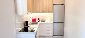 A compact kitchen with a built-in oven, a sink, and a refrigerator. - Premium apartment in Acropolis (Athens)