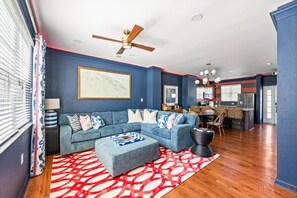 Ein Wohnzimmer mit Ecksofa, Couchtisch und einem roten Teppich mit Muster.