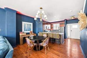 A modern kitchen with a central island, a dining area with a round table and chairs, and a living area with a sofa. - Flames Fan House | *3 MIN to LU* | Sleeps 10! (Lynchburg)