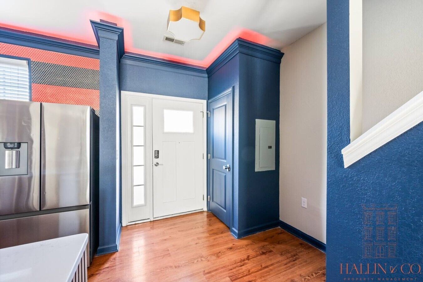 A room with a kitchen area, a white door, and a blue wall.