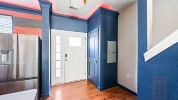 Una habitación con área de cocina, una puerta blanca y una pared azul.