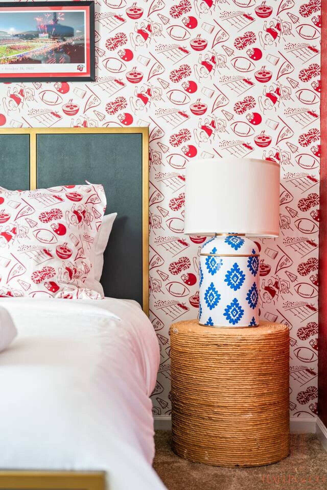 A bedroom with a bed, a nightstand with a lamp, and a patterned wallpaper.