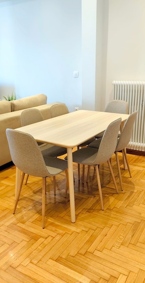 A dining area with a wooden table and chairs, a sofa, and a radiator. - Sunny home in Acropolis (Athens)