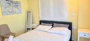 A hotel room with a bed, bedside tables, a chair, a mirror, and a painting on the wall. - Sunny home in Acropolis (Athens)