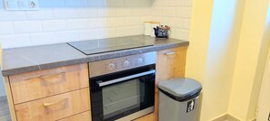 A kitchen with a countertop, oven, and trash bin. - Sunny home in Acropolis (Athens)