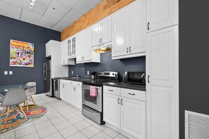 A modern kitchen with white cabinets, stainless steel appliances, and a wooden ceiling. - Boutique-Style Studio in the heart of the Old Port (Montréal)