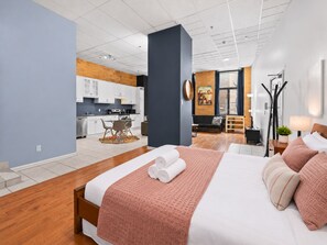 A modern hotel room with a large bed, a dining area, and a kitchen in the background. - Boutique-Style Studio in the heart of the Old Port (Montréal)