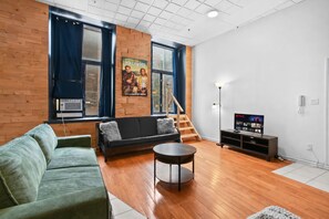 A living room with a sofa, a coffee table, a TV, and a staircase. - Boutique-Style Studio in the heart of the Old Port (Montréal)