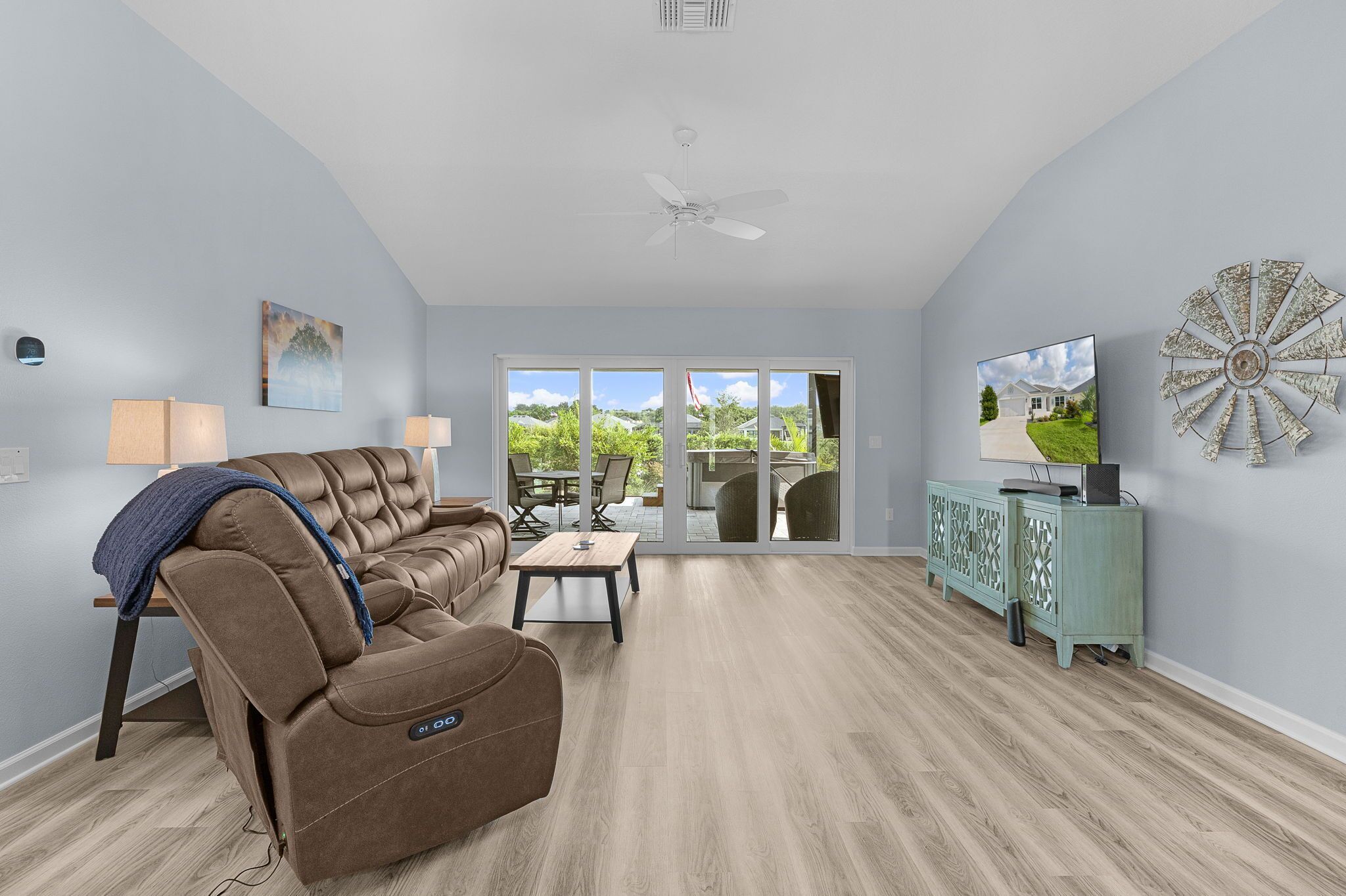 A spacious living room with a brown leather sofa, a dining table, and a TV on a cabinet.