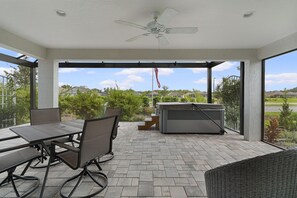 Un patio al aire libre con una mesa, sillas, un ventilador de techo y un jacuzzi.