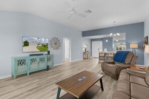 Ein Wohnzimmer mit Fernseher, Couchtisch, Sofa und Deckenventilator.