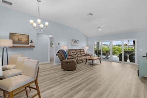 Un salón amplio con un sofá grande, una mesa de centro y un comedor con mobiliario de exterior.
