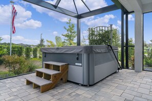 Un patio couvert avec un jacuzzi, des marches en bois et une vue sur un quartier résidentiel.