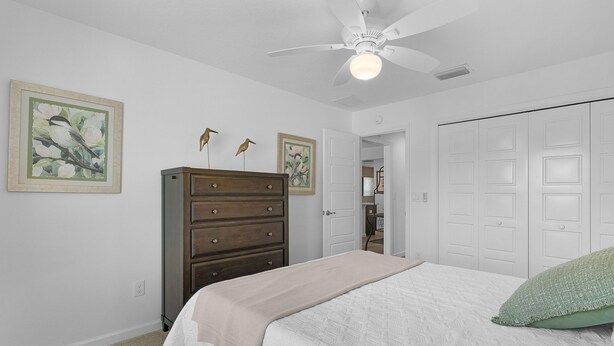 A bedroom with a bed, dresser, and two wall-mounted bird paintings. - Dog-Friendly Citrus Grove Home with Golf Cart, Fenced Yard & Lanai (The Villages)