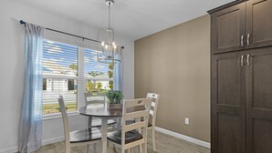 A dining area with a table and chairs, a window with blinds, a ceiling light fixture, and a cabinet. - Dog-Friendly Citrus Grove Home with Golf Cart, Fenced Yard & Lanai (The Villages)