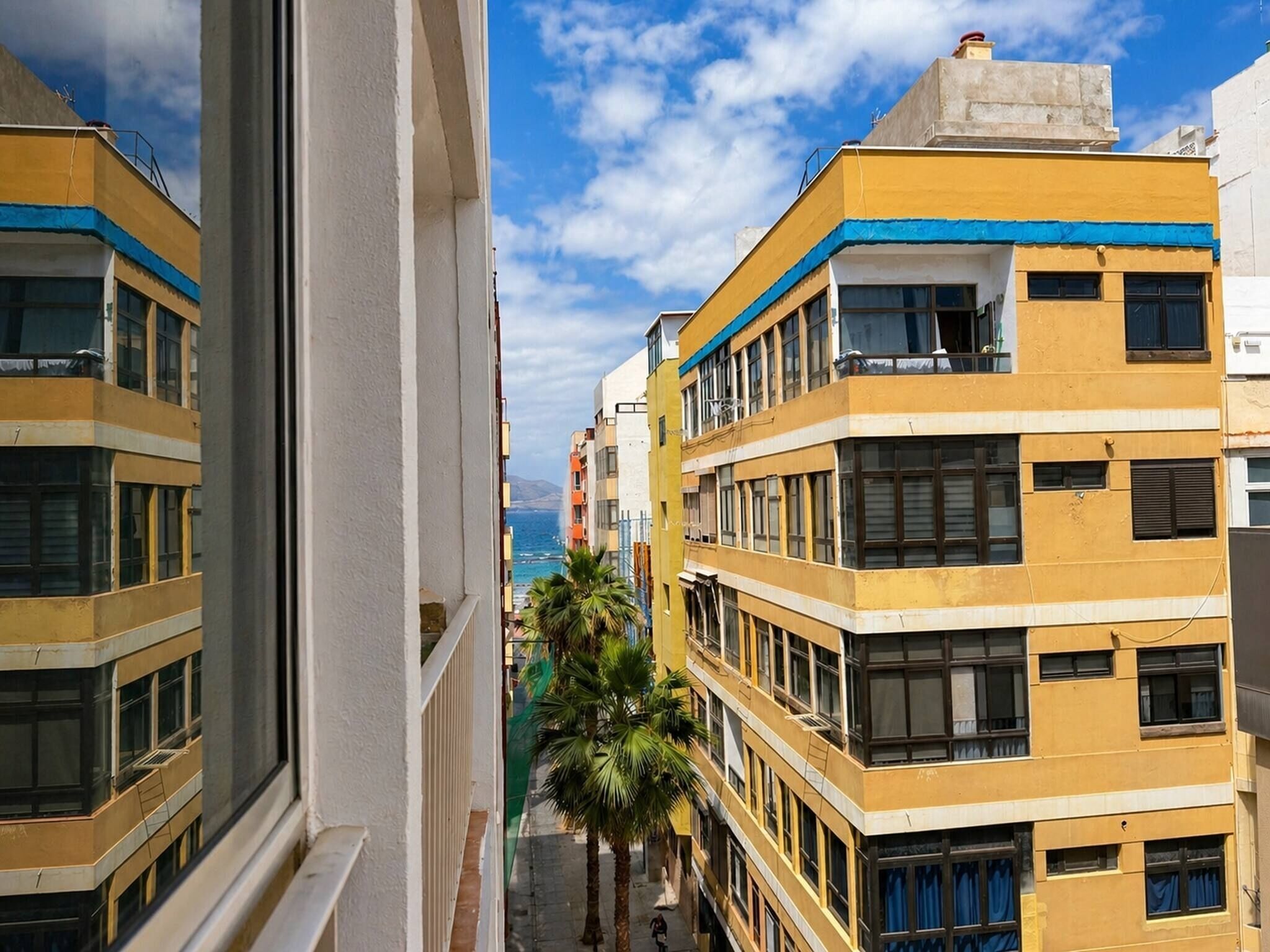 Un edificio de varios pisos con balcones, cielo despejado y vista al mar.