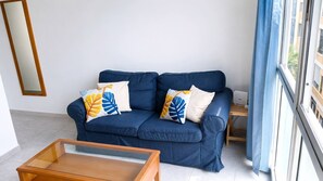 A blue sofa with leaf-patterned cushions, a wooden coffee table, and a mirror on the wall. - Las Canteras | 1 Min to the Beach | Ocean View | 2 Guests (Las Palmas de Gran Canaria)