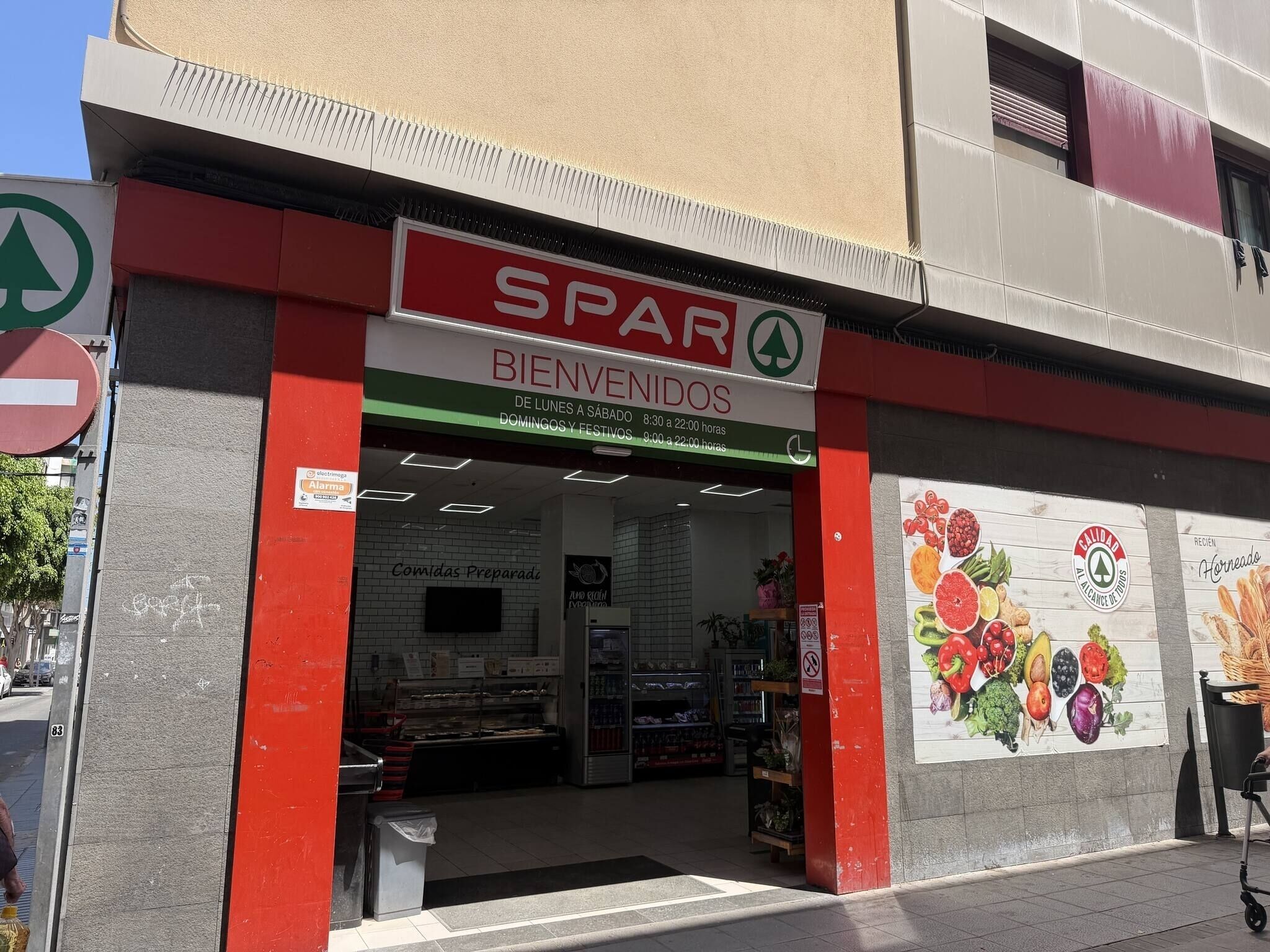 A storefront with a red and white sign reading 'SPAR BIENVENIDOS' and a green arrow sign.