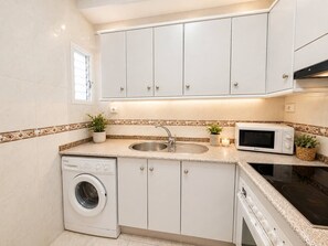 A compact kitchen with a washing machine, a microwave, and a stove. - Las Canteras | 1 min to the beach | Ocean view | For 2 guests (Las Palmas de Gran Canaria)