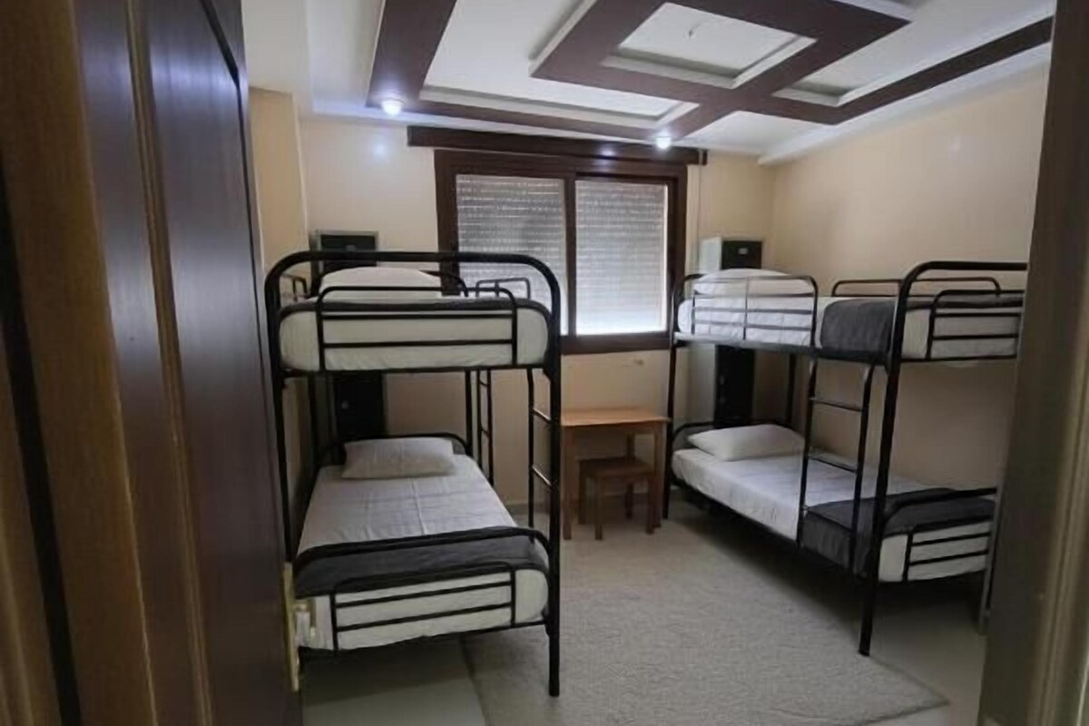 A room with bunk beds, a desk, and a window.