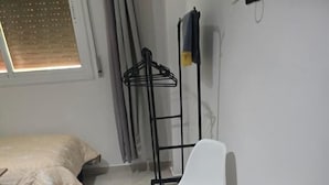 A room with a bed, two white chairs, a patterned rug, and a coat rack. - Hostel Dar Khelifa (TÉTOUAN)