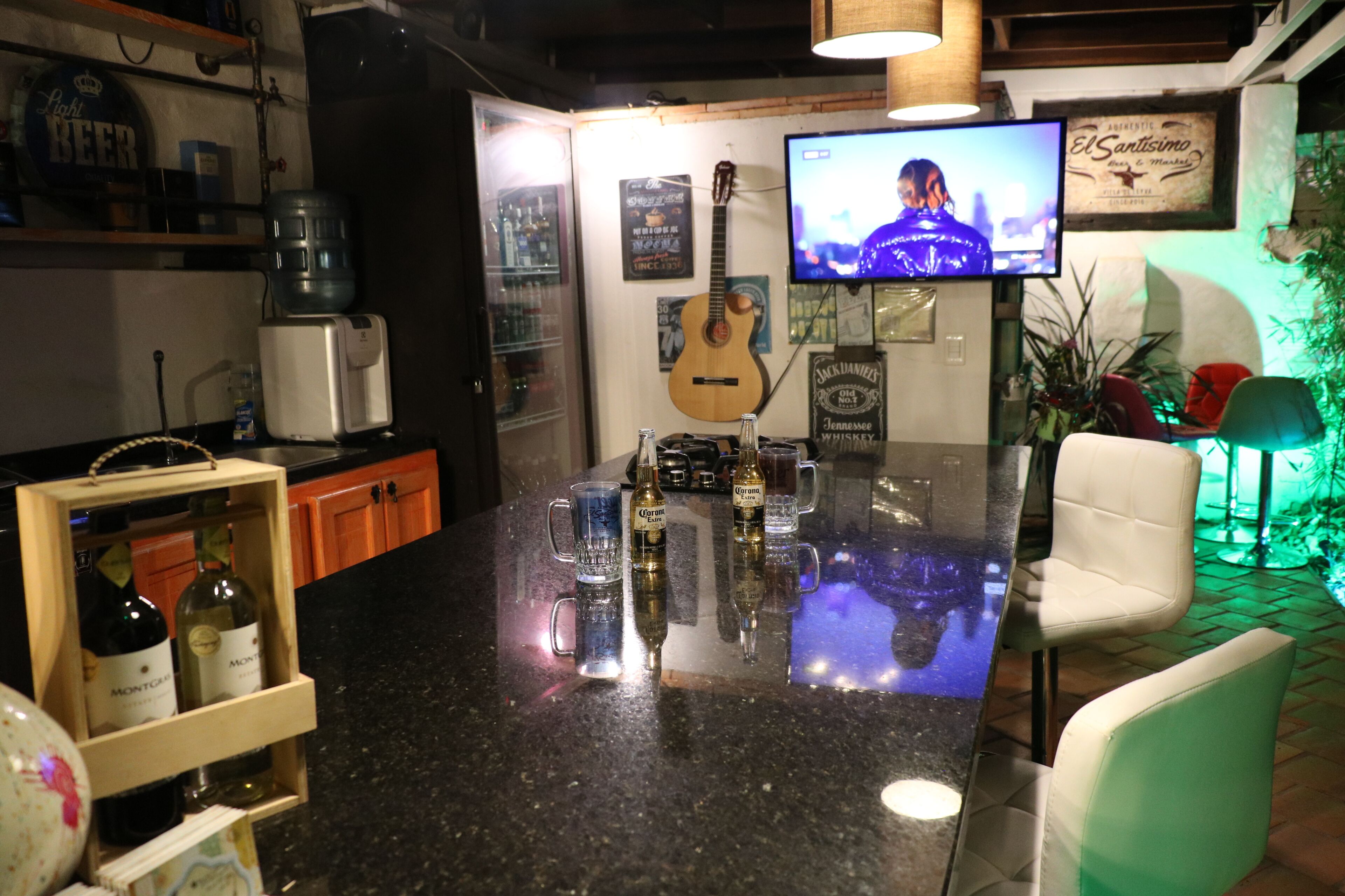 Zona de bar con televisor, una guitarra y varias botellas.