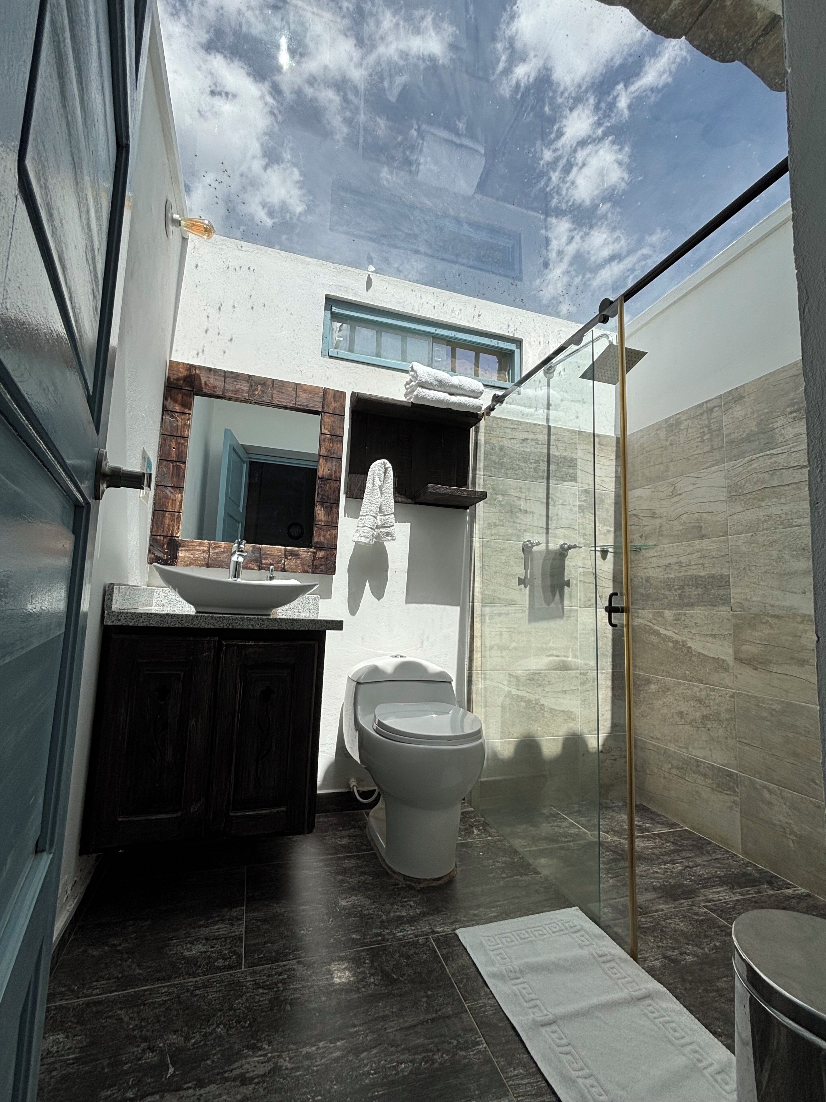 Ein modernes Badezimmer mit einer Duschkabine aus Glas, einer weißen Toilette und einem Waschtisch mit Spiegel.