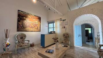 A room with a wooden floor, a painting on the wall, a blue door, and a white archway.