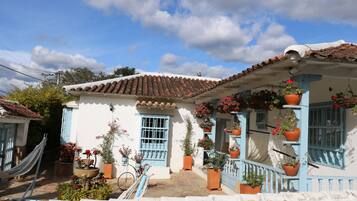 A traditional house with a tiled roof, blue window frames, and potted plants.