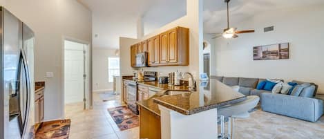 A modern kitchen with granite countertops, wooden cabinets, and a built-in island.